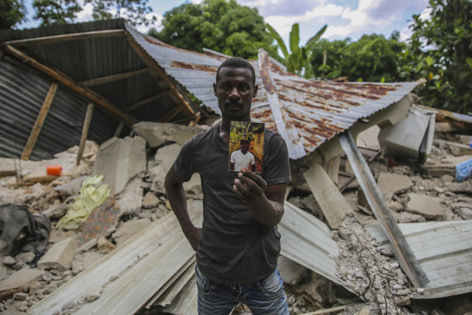 Greogory Andre shows a photo of his brother Remossa Andre, who died during the earthquake in Camp-Perrin, Les Cayes, Haiti, Sunday, Aug. 15, 2021. A 7.2 magnitude earthquake struck Haiti on Saturday, with the epicenter about 125 kilometers (78 miles ) west of the capital of Port-au-Prince, the US Geological Survey said. (AP Photo/Joseph Odelyn)