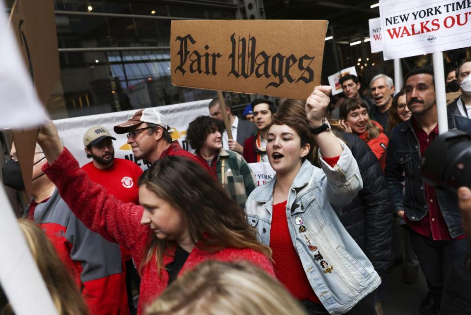 A woman in a crowd holds a sign calling for "Fair Wages."