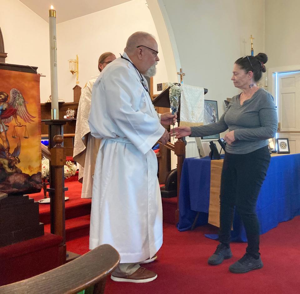 Vienna Moon-Kline, daughter of slain Hagerstown Police Officer Donald Ralph "Barney" Kline, receives a flower from Fraternal Order of Police Thomas Pangborn Lodge #88 Chaplain Chuck Kauffman during last week's service at St. Andrew's Episcopal Church in Clear Spring to honor law enforcement officers who gave their lives in the line of duty.