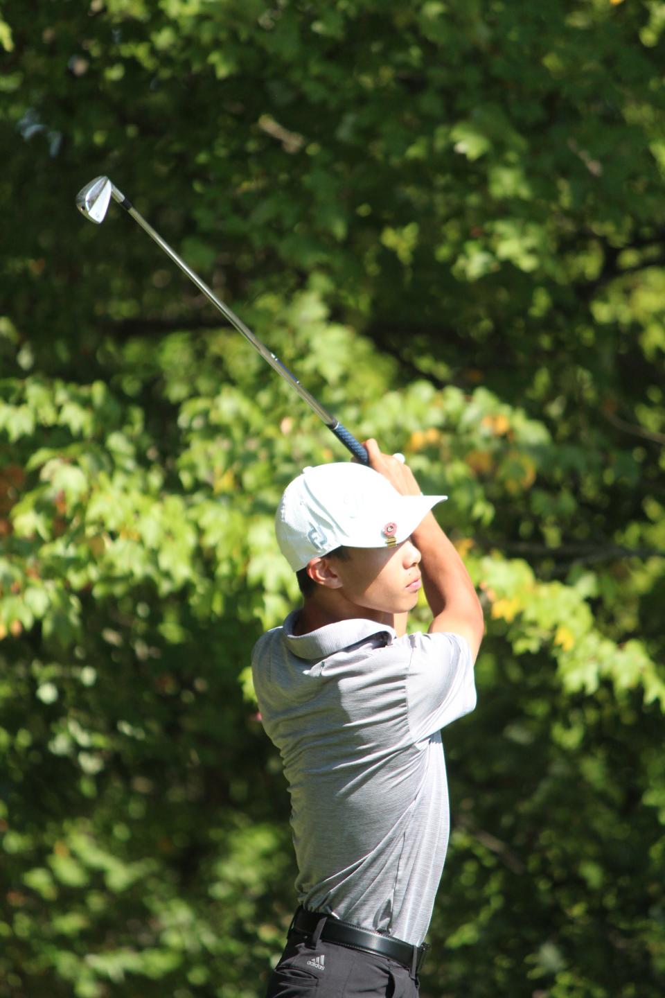 Quaker Valley's Ethan Dai hits an iron shot between two trees at Butler Country Club.