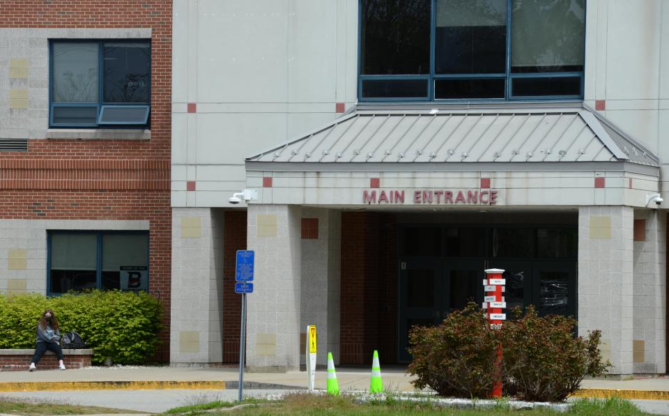 A lone student waits outside the main entrance to Barnstable High School which closed in May because of a COVID-related staff shortage. Steve Heaslip/Cape Cod Times