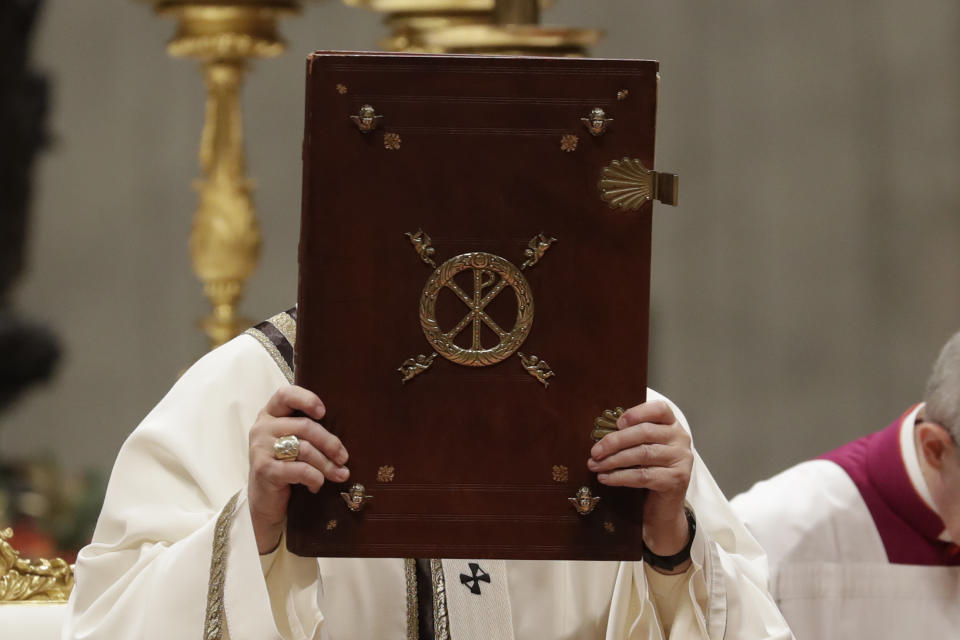 Pope Francis holds up the book of Gospels as he celebrates Christmas Eve Mass in St. Peter's Basilica at the Vatican, Tuesday, Dec. 24, 2019. (AP Photo/Alessandra Tarantino)