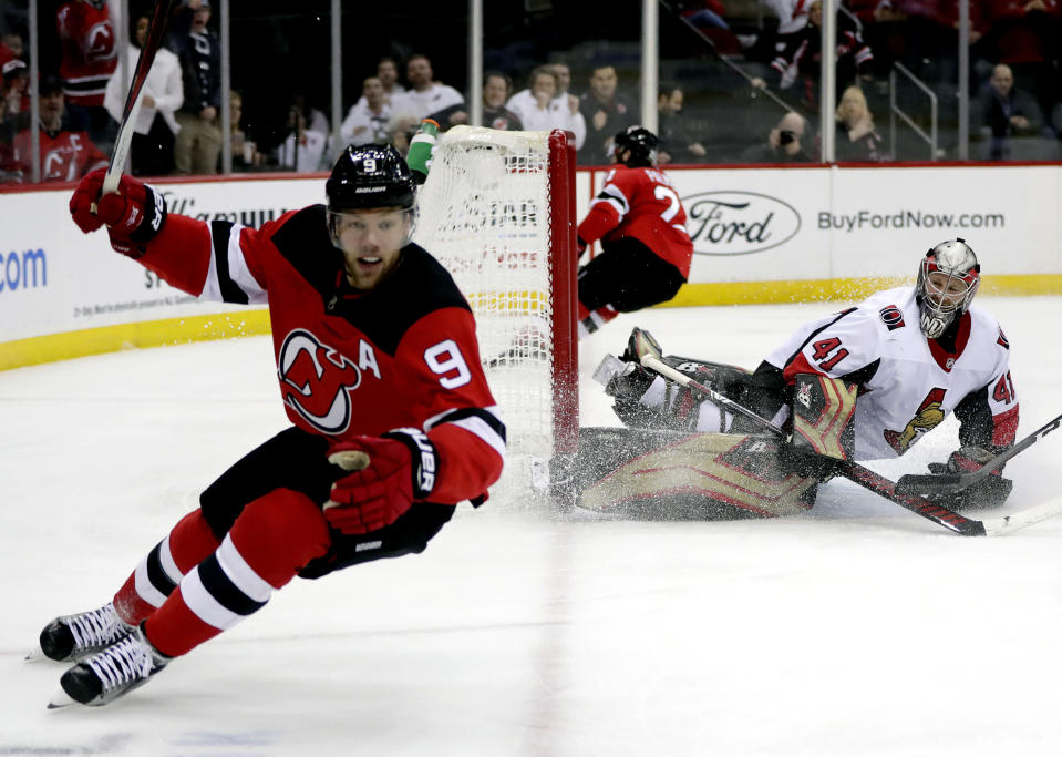 FILE - In this Dec. 21, 2018, file photo, Ottawa Senators goaltender Craig Anderson right, watches as New Jersey Devils left wing Taylor Hall (9) celebrates after scoring a goal during the second period of an NHL hockey game in Newark, N.J. The Devils are doing all they can to make sure Hall re-signs long term rather than leaving in free agency next summer. (AP Photo/Julio Cortez, File)