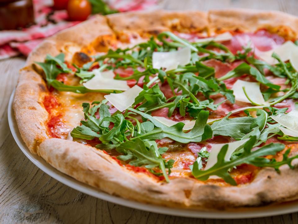 thin crust pizza topped with arugula and Parmesan cheese