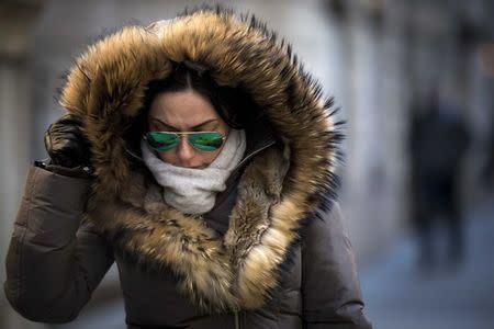 A woman shields herself as she walks through the cold and wind in New York's financial district February 13, 2015. REUTERS/Brendan McDermid