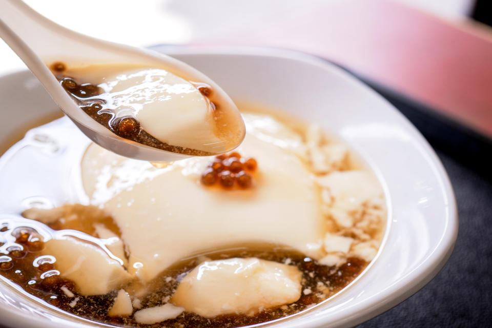 Popular Taiwan gourmet - Dessert of tapioca pearl ball (bubble) mixed bean curd tofu pudding (douhua, dou hua) in white bowl, close up, lifestyle