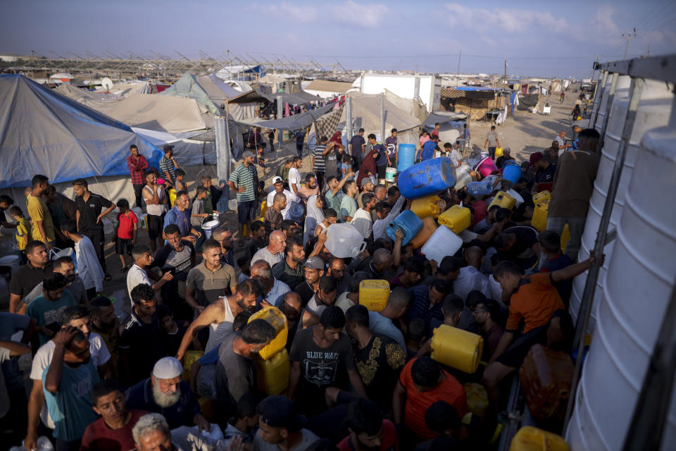 Palestinians displaced by the Israeli bombardment of the Gaza Strip queue for water at a makeshift tent camp in the southern town of Khan Younis, Monday, July 1, 2024. (AP Photo/Jehad Alshrafi)