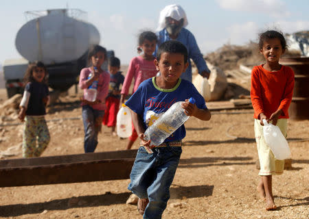 Palestinian children carry water bottles near their house on the outskirts of the West Bank village of Yatta, south of Hebron, August 17, 2016. REUTERS/Mussa Qawasma