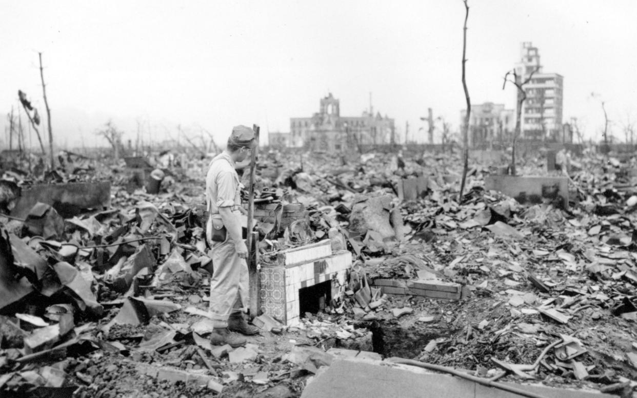 A man stands next to a tiled fireplace where a house once stood in Hiroshima - AP Photo/Stanley Troutman, Pool, File