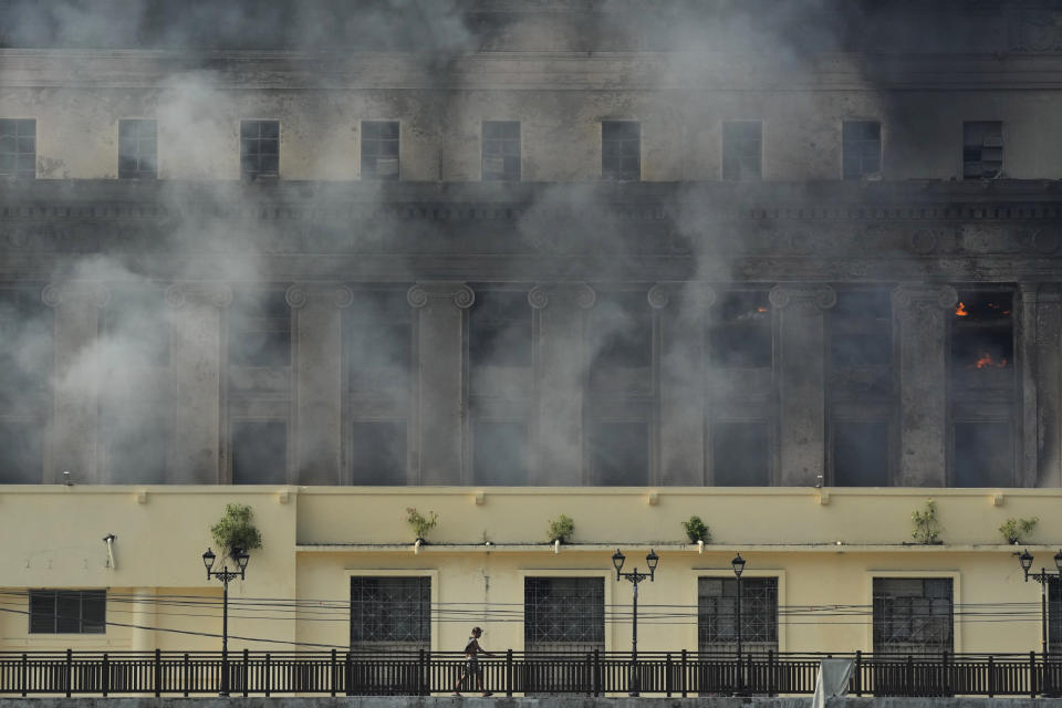 FILE - A man passes by the still smoldering Manila Central Post Office after it caught fire early Monday, May 22, 2023 in Manila, Philippines. On Friday, July 7, The Associated Press reported on stories circulating online incorrectly claiming a video shows a major library in France burning during riots sparked by the police killing of a 17-year-old. (AP Photo/Aaron Favila, File)
