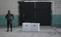 Soldiers guard boxes of electoral ballots after the closing of a voting center during general elections in Tegucigalpa, Honduras, Sunday, Nov. 28, 2021. The National Electoral Council called on political parties to refrain from declaring their candidates victorious or providing partial vote totals while voting was ongoing. (AP Photo/Moises Castillo)