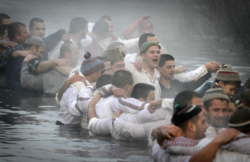 Believers sing and dance in the river Tundzha, as they celebrate Epiphany day in the town of Kalofer, Bulgaria, Monday, Jan. 6, 2014. Traditionally, an Eastern Orthodox priest throws a cross in the river and it is believed that the one who retrieves it will be healthy through the year. (AP Photo/Valentina Petrova)