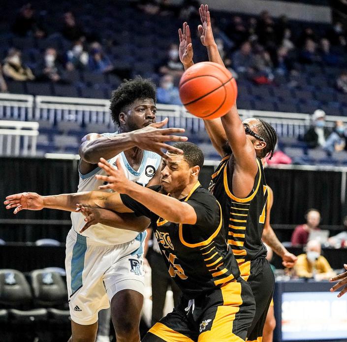 URI&#39;s Makhi Mitchell passes around American International defenders in the second half of Sunday&#39;s game in Kingston.