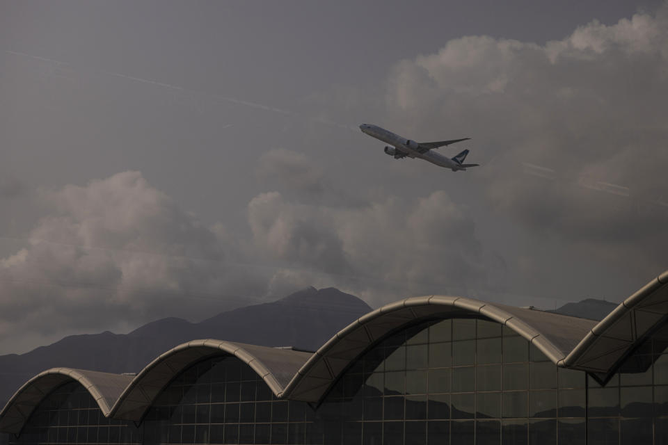 An aircraft operated by Cathay Pacific Airways is seen through glass as it takes off from Hong Kong International Airport in Hong Kong, on Wednesday, March. 8, 2023. Cathay Pacific Airways Ltd. said it was ready to rebuild as Hong Kong opened up to global visitors, despite reporting wider losses in 2022. (AP Photo/Louise Delmotte)