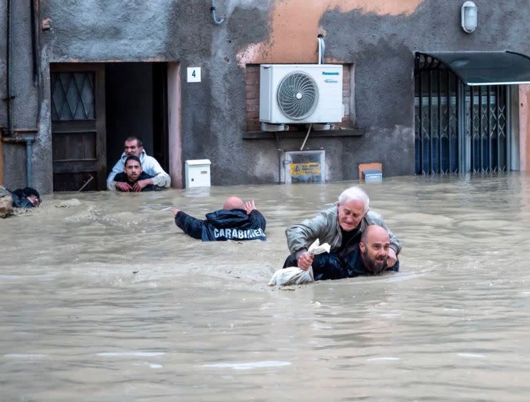 Miembros de la gendarmería nacional de Italia llevan a los residentes a cuestas por las calles inundadas