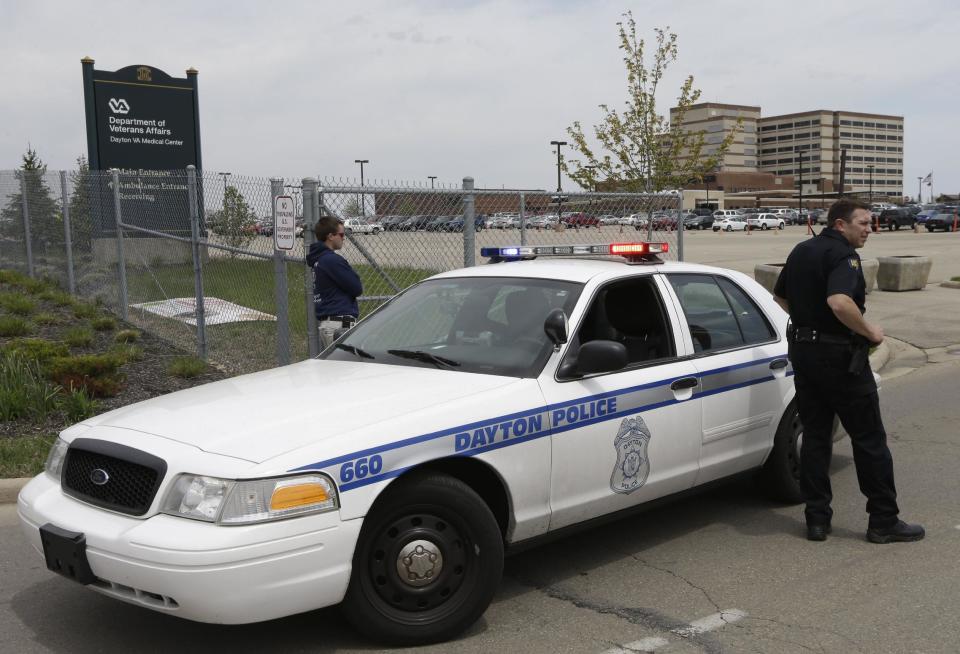 A police officer blocks the entrance to a Veterans Affairs hospital after the building seen at right rear was locked down after a shooting, Monday, May 5, 2014, in Dayton, Ohio. A city official says a suspect is in police custody after the shooting that left one person with a minor injury. (AP Photo/Al Behrman)