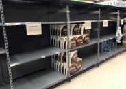 Empty shelves are seen next to supplies of toilet roll inside an Asda supermarket in Milton Keynes