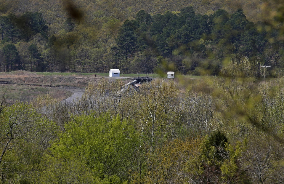 In this April 8, 2019, photo, a chute to dump coal waste at the open heap of toxic fly ash can be seen through the trees of a nearby home in Bokoshe, Okla. Residents of Bokoshe have been worried for years about coal-ash contamination. Now the Environmental Protection Agency has approved Oklahoma to be the first state to take over enforcement on coal-ash sites. (AP Photo/Sue Ogrocki)