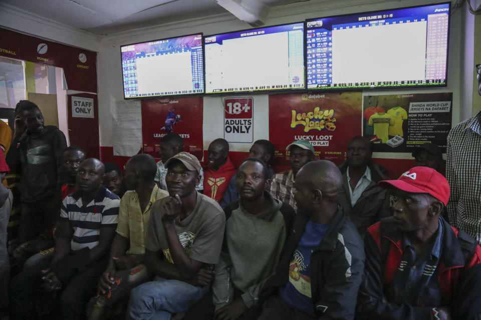 Customers watch screens in a sports betting shop in the low-income Kibera neighborhood of the capital Nairobi, Kenya, Monday, Dec. 5, 2022. Although sports betting is a global phenomenon and a legitimate business in many countries, the stakes are high on the continent of 1.3 billion people because of lax or non-existent regulation, poverty and widespread unemployment. (AP Photo/Brian Inganga)