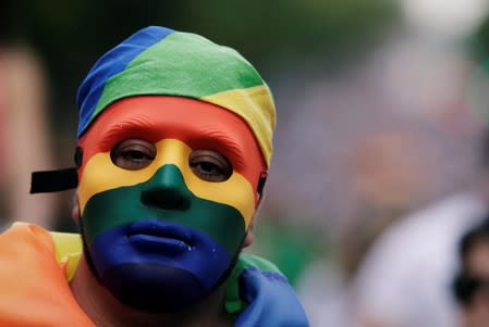 A man wearing a mask with the colors of the rainbow flag takes part in the annual Gay Pride parade along a Central Avenue, in San Jose