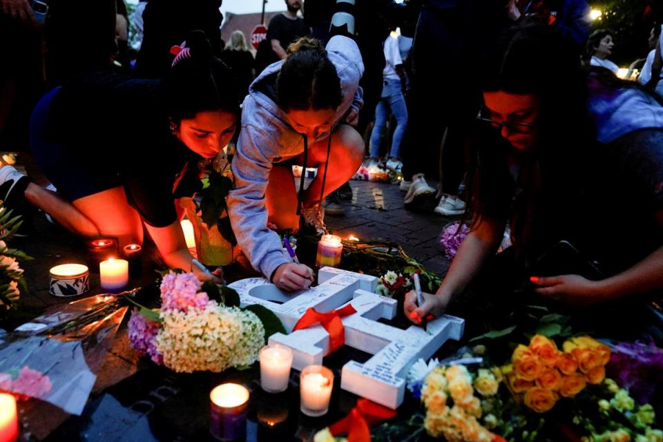 Community members write messages at a memorial site near the parade route the day after the mass shooting (REUTERS)