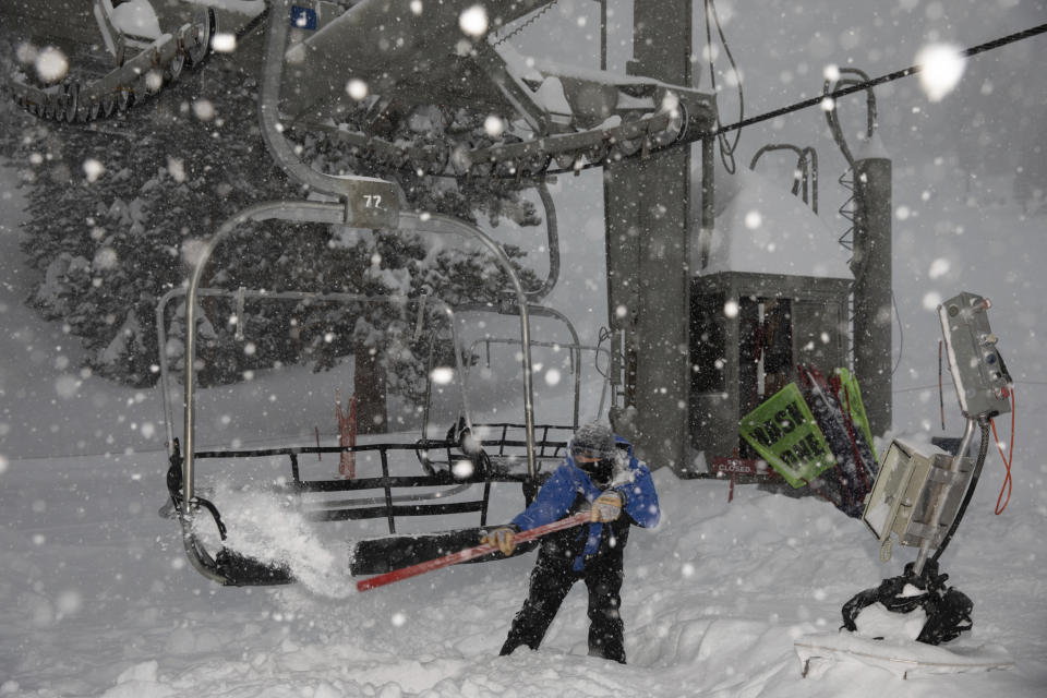 In this photo provided by Mammoth Mountain Ski Area, clears snow from a lift area during a heavy snowfall at Mammoth Mountain Ski Area in Mammoth Lakes, Calif on Thursday, Jan. 28, 2021. In the Eastern Sierra, the Mammoth Mountain ski resort reported 7.25 feet (2.21 meters) of new snow on its summit. A blizzard warning continued for both sides of the California-Nevada border along a 170-mile (274-kilometer) stretch of the Sierra. (Christian Pondella/ Mammoth Mountain Ski Area via AP)