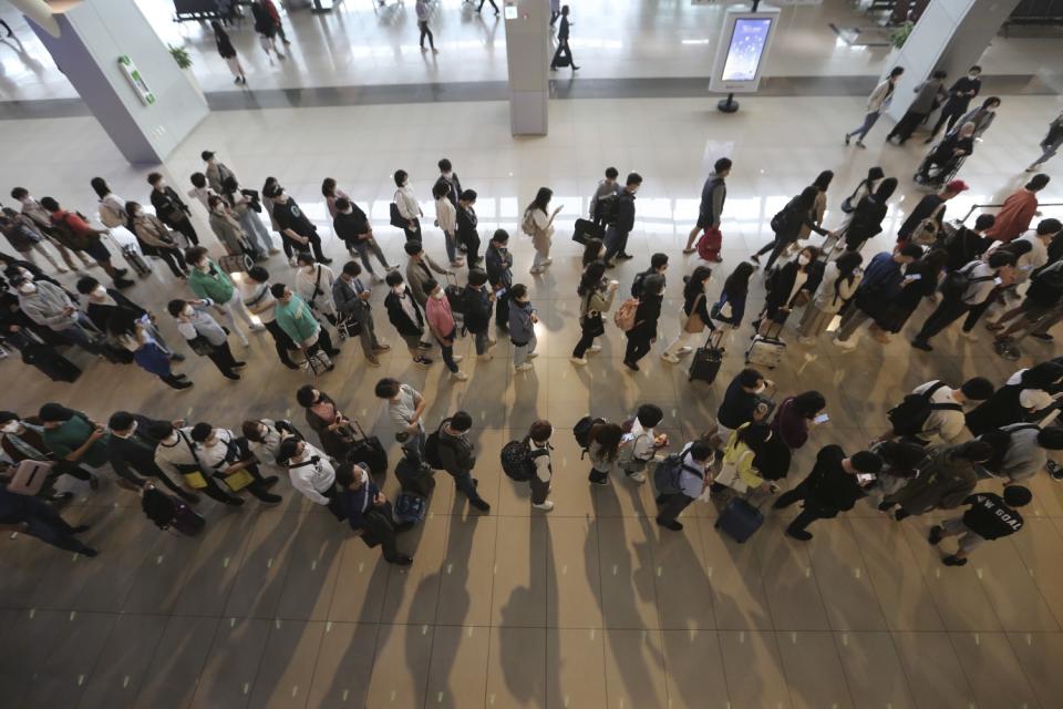 Passengers line up at an airport to board planes.