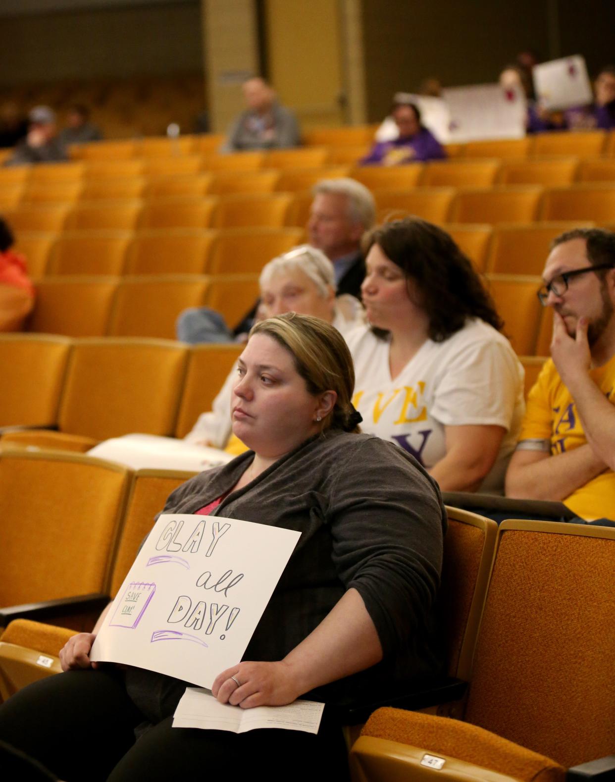 Several people in the audience hold signs in opposition of closing Clay High School at the South Bend school board meeting Monday, March 20, 2023, at Clay High School.  Consultants recommended closure of Clay High School and Warren School in its facilities study findings to the board.