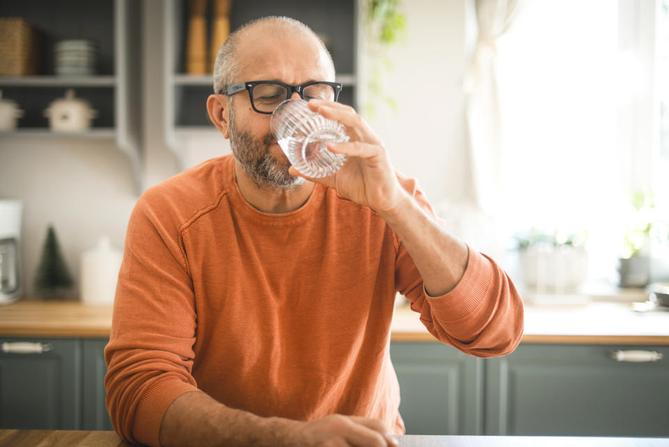 Man with a cold drinking water. (Getty Images)