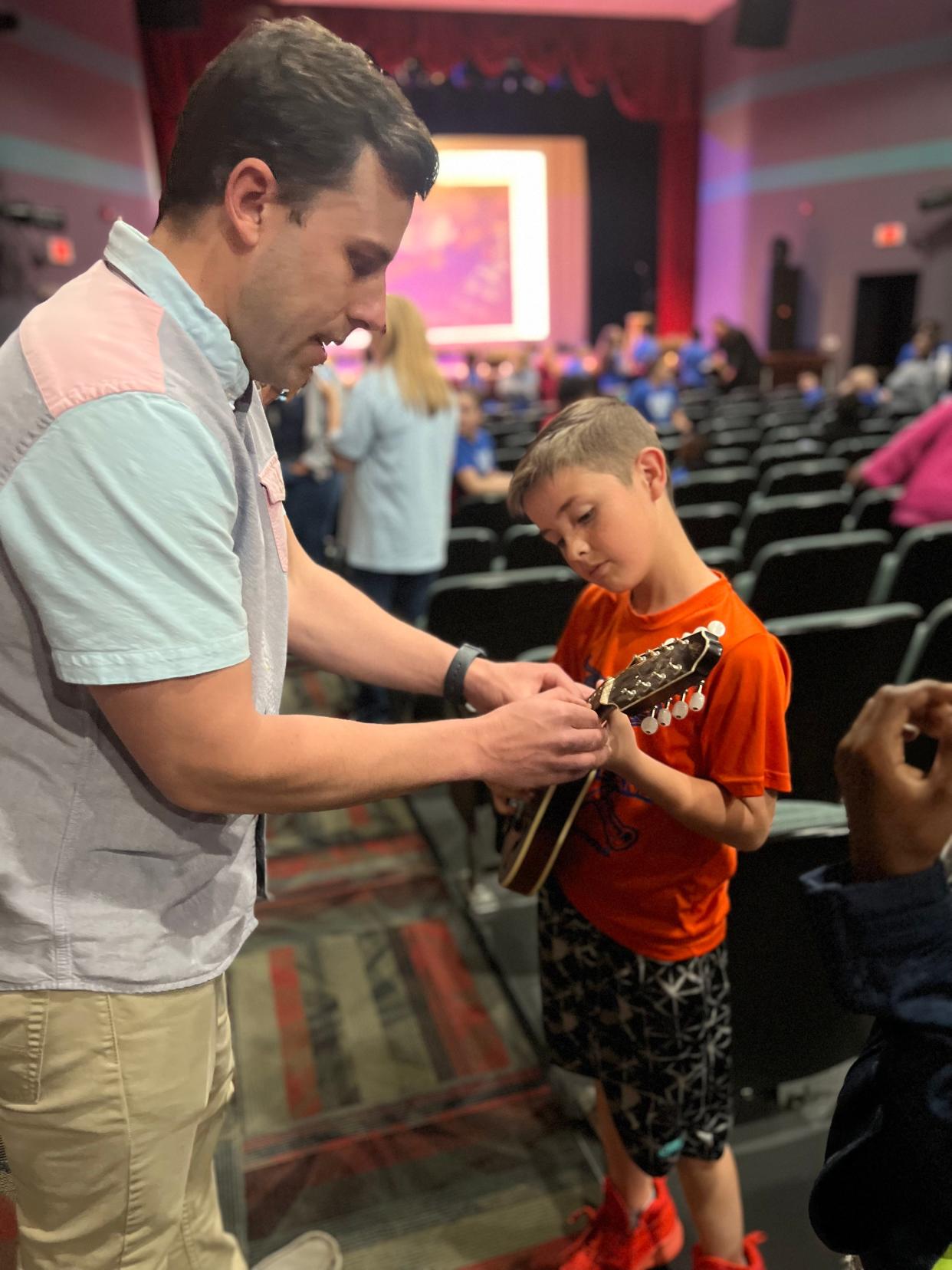 Earl Scruggs Center Assistant Director Zach Dressel shows a student how to hold and play a mandolin during the Bluegrass Ambassadors program at the Don Gibson Theater on Tuesday.
