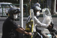 People on their motorcycles wearing protective face masks to help prevent the spread of the coronavirus wait for a green light at an intersection in downtown Tehran, Iran, Sunday, Sept. 20, 2020. Iran's president dismissed U.S. efforts to restore all U.N. sanctions on the country as mounting economic pressure from Washington pushed the local currency down to its lowest level ever on Sunday. (AP Photo/Vahid Salemi)
