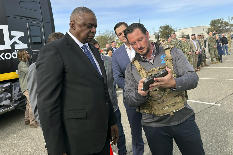 Defense Secretary Lloyd Austin takes a closer look at the device used to control a swarm of drones that lifted off from a parking area at the Defense Innovation Unit in Mountain View, Calif, on Friday, Dec. 1, 2023. Austin is in California for meeting with defense ministers from Australia and the United Kingdom, but took some time to see several projects under development at DIU. (AP Photo/Lolita Baldor)