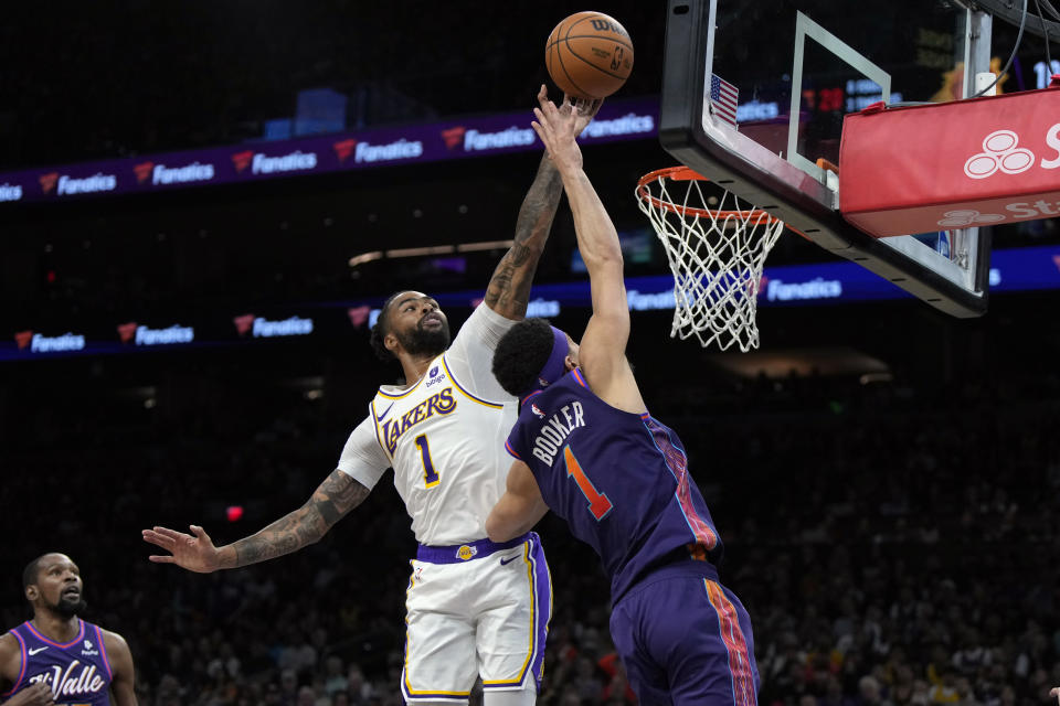 Phoenix Suns guard Devin Booker, right, has his shot blocked by Los Angeles Lakers guard D'Angelo Russell, center left, during the second half of an NBA basketball game, Sunday, Feb. 25, 2024, in Phoenix. (AP Photo/Rick Scuteri)