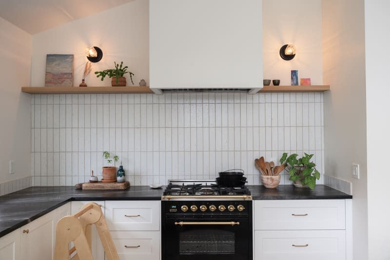 White tile backsplash behind black stove in kitchen.