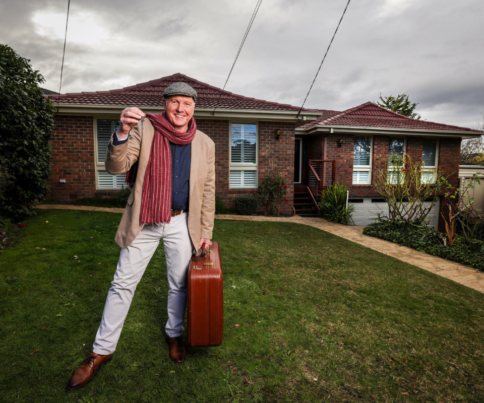 Alan Fletcher stands on the front lawn of 28 Ramsay St holding the keys to the house and a suitcase.