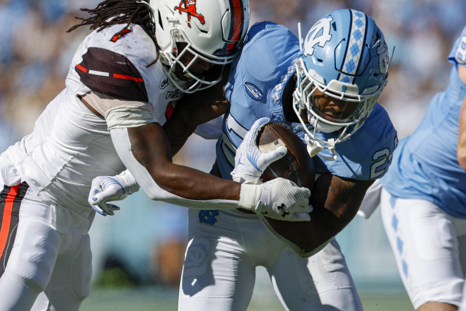 North Carolina running back British Brooks (24) fights for yardage as he is tackled by Campbell linebacker Monchovia Gaffney in the first half of an NCAA college football game in Chapel Hill, N.C., Saturday, Nov. 4, 2023. (AP Photo/Nell Redmond)
