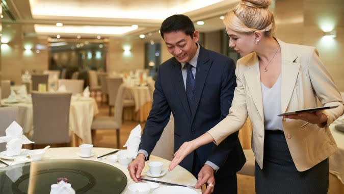 Wedding planner and banquet manager discussing table setting.