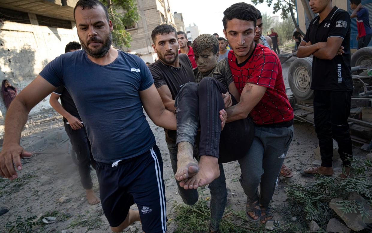 Palestinians carry a person wounded in Israeli airstrikes in Khan Younis, Gaza Strip, Monday, Oct. 16, 2023.