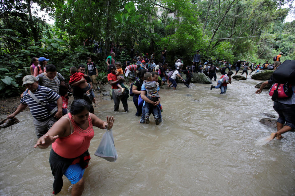 People clutch children and belongings as they wade through currents.