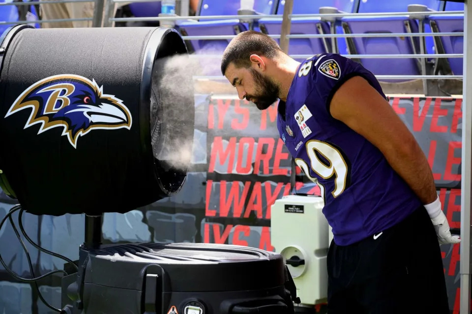 PHOTO: Baltimore Ravens tight end Mark Andrews gets relief from the heat next to a water mister during the team's NFL football training camp, July 29, 2023, in Baltimore. (Nick Wass/AP)