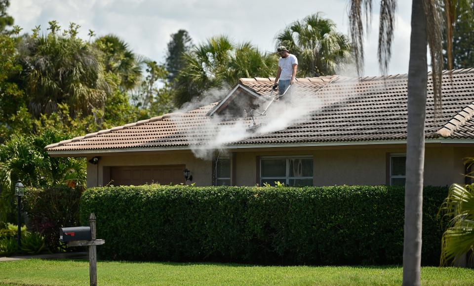 A worker cleans the tile roof of a home in Gulf Gate.