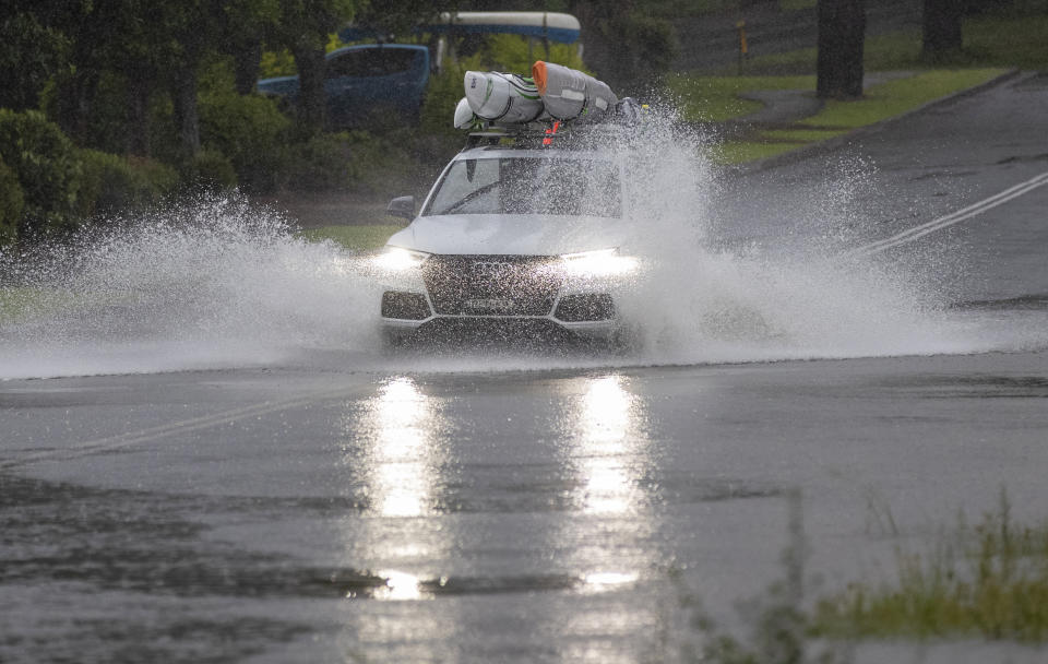 A car plows through water on a flooded road at Port Stephens, 200 kilometers (120 miles) north of Sydney, Australia, Sunday, March 21, 2021. Residents across the state of New South Wales have been warned to prepare for possible evacuations, as NSW Premier Gladys Berejiklian said the state's flood crisis would continue for several more days. (AP Photo/Mark Baker)