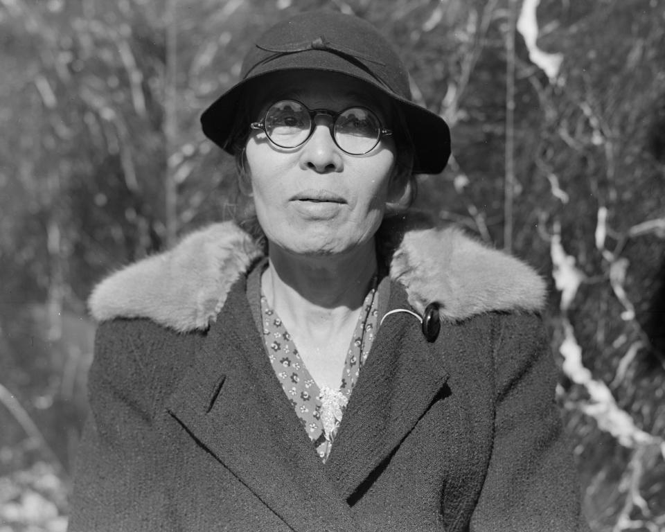 In this photo provided by the National Archives, a woman arrives at 2020 Van Ness Avenue in San Francisco, as part of the contingent of 664 residents of Japanese ancestry first to be relocated from the city on April 6, 1942, to an internment camp for Japanese Americans during World War II. (Dorothea Lange/War Relocation Authority/National Archives via AP)