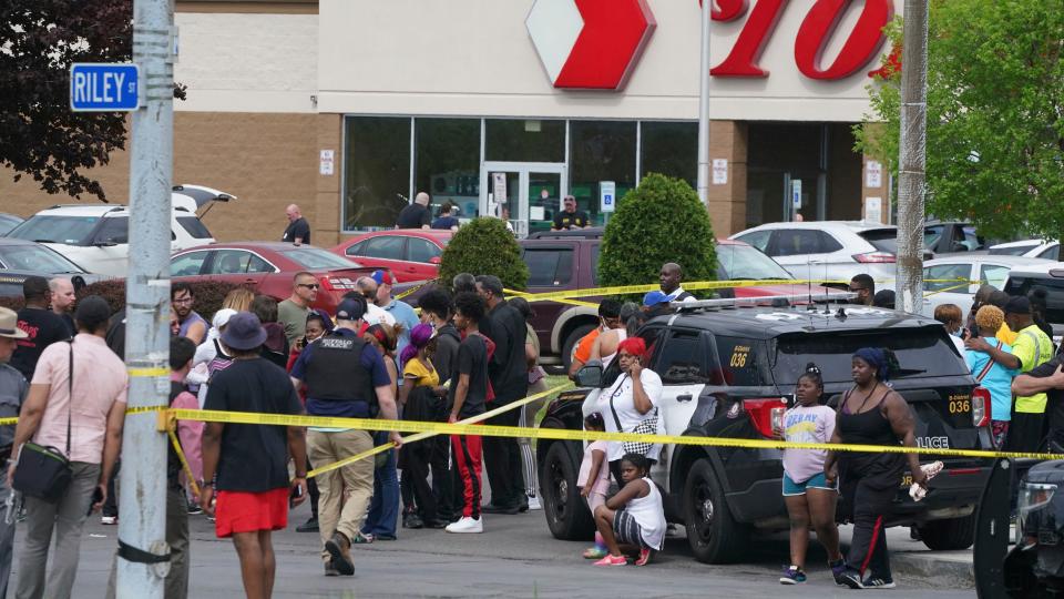 People gather outside a supermarket where several people were killed in a shooting, Saturday, May 14, 2022 in Buffalo, N.Y. Officials said the gunman entered the supermarket with a rifle and opened fire. Investigators believe the man may have been livestreaming the shooting and were looking into whether he had posted a manifesto online (Derek Gee/The Buffalo News via AP)
