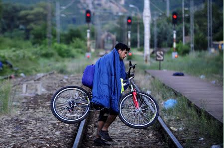 A migrant from Syria carries his bicycle on railway near the Greek border in Macedonia June 17, 2015. REUTERS/Ognen Teofilovski