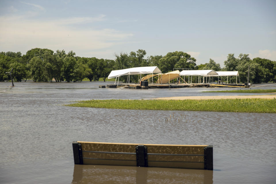 FILE - A bench sits in floodwaters as the the Missouri River boat club is overrun by flooding in Sioux City, Iowa, June 24, 2024. Record flooding and powerful tornadoes ravaged parts of Iowa for weeks this spring, destroying or damaging thousands of homes, closing roads and bridges and costing over $130 million in infrastructure damage, officials said Thursday, July 11. (AP Photo/Josh Jurgens, File)