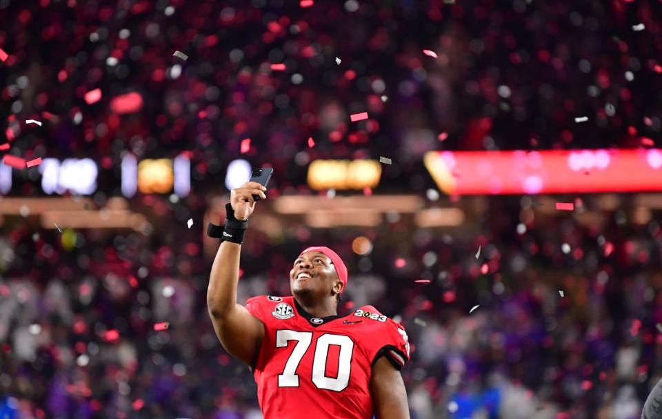 Georgia offensive lineman Warren McClendon takes photos of the confetti after defeating TCU in the College Football Playoff final.