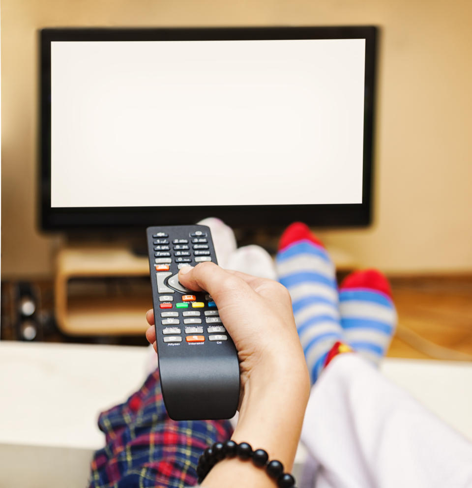 Close-up of a Hand Holding a Remote Control, TV showing white blank screen.