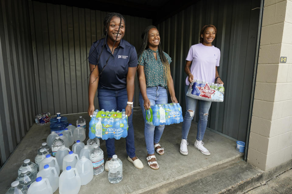 Mississippi Students Water Crisis Advocacy Team members, Jordyn Jackson, 21, left, coordinator Maisie Brown, 20, center, and Mya Grimes, 18, all students at Jackson State University, share a laugh as they carry out cases from their Jackson, Miss., storage locker for home delivery, Sept. 8, 2022. A boil-water advisory has been lifted for Mississippi's capital, and the state will stop handing out free bottled water on Saturday. But the crisis isn't over. Water pressure still hasn't been fully restored in Jackson, and some residents say their tap water still comes out looking dirty and smelling like sewage. (AP Photo/Rogelio V. Solis)