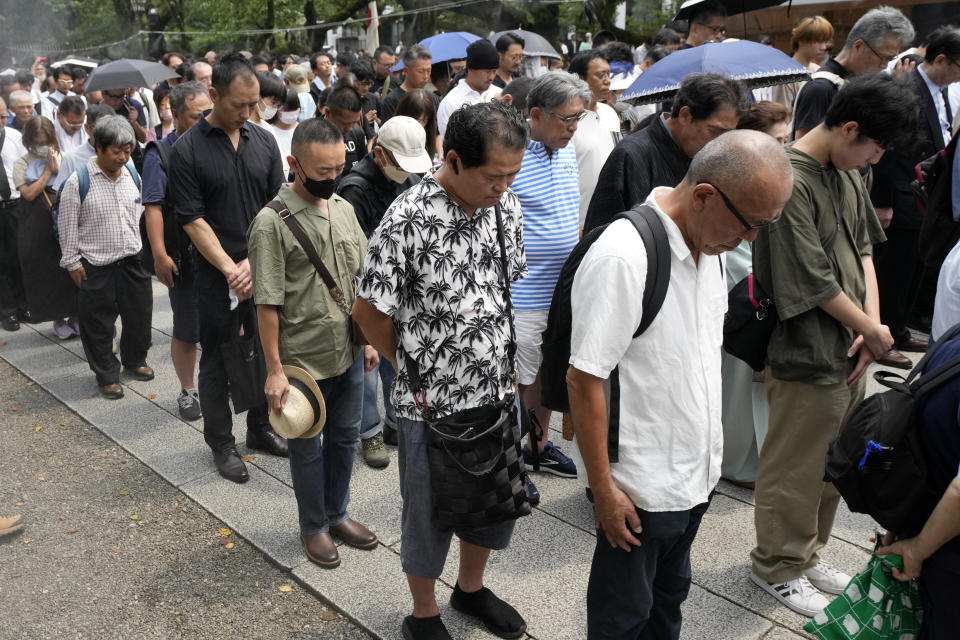 Visitors observe a minute of silence at noon at the Yasukuni Shrine, which honors Japan's war dead, Tuesday, Aug. 15, 2023, in Tokyo, Japan. Japan holds annual memorial service for the war dead as the country marks the 78th anniversary of its defeat in the World War II. (AP Photo/Eugene Hoshiko)